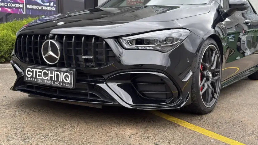 Black Mercedes-Benz AMG car with Gtechniq plate outside a detailing shop.