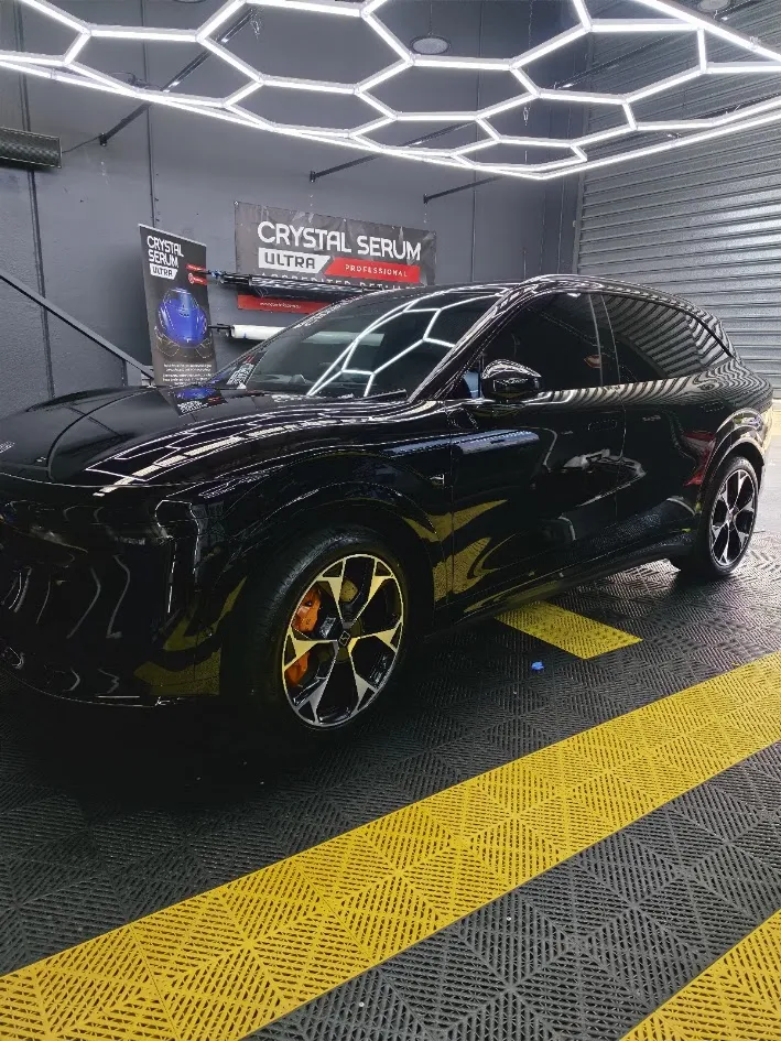Professional installer applying ceramic window tint to a car window, demonstrating expert techniques