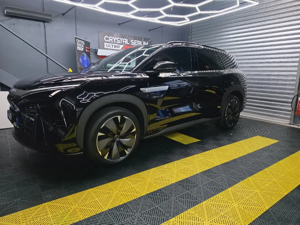 Technician applying ceramic coating on a freshly polished car in a professional workspace